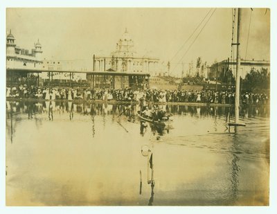 Fotografía horizontal de un nadador cruzando la línea de meta. Hombres en un bote observan, así como multitudes de personas en la orilla de Unknown